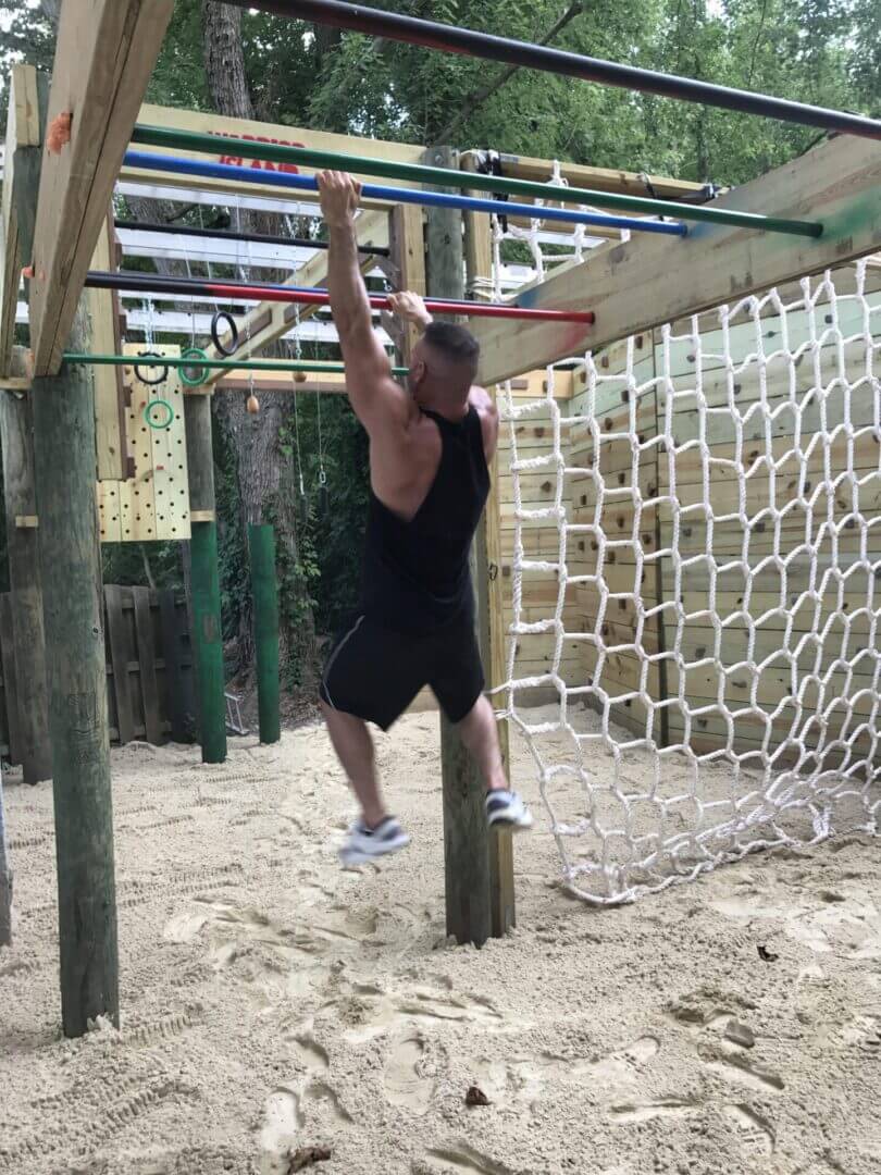 Warrior swinging through the rig at the Warrior Island obstacle course