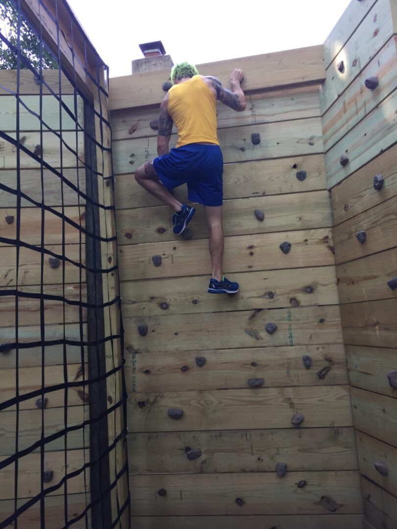 Warrior climbing the rock wall on the Warrior Island obstacle course
